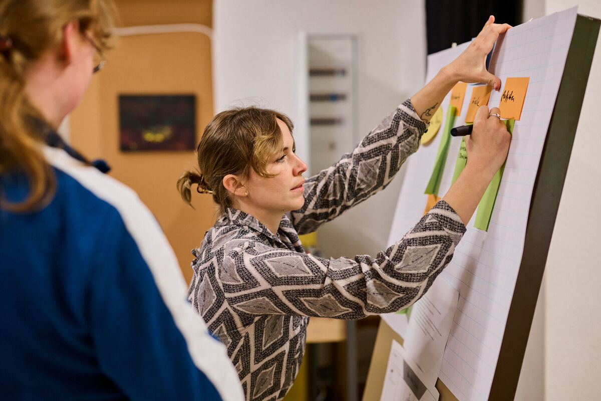 Zwei Frauen in einem Workshop, erarbeiten eine Strategie für die Implementierung von Suchtechnologien, wie Facettenfilter und personalisierte Sucherlebnisse, zur Optimierung von Online-Plattformen und Nutzererfahrungen.