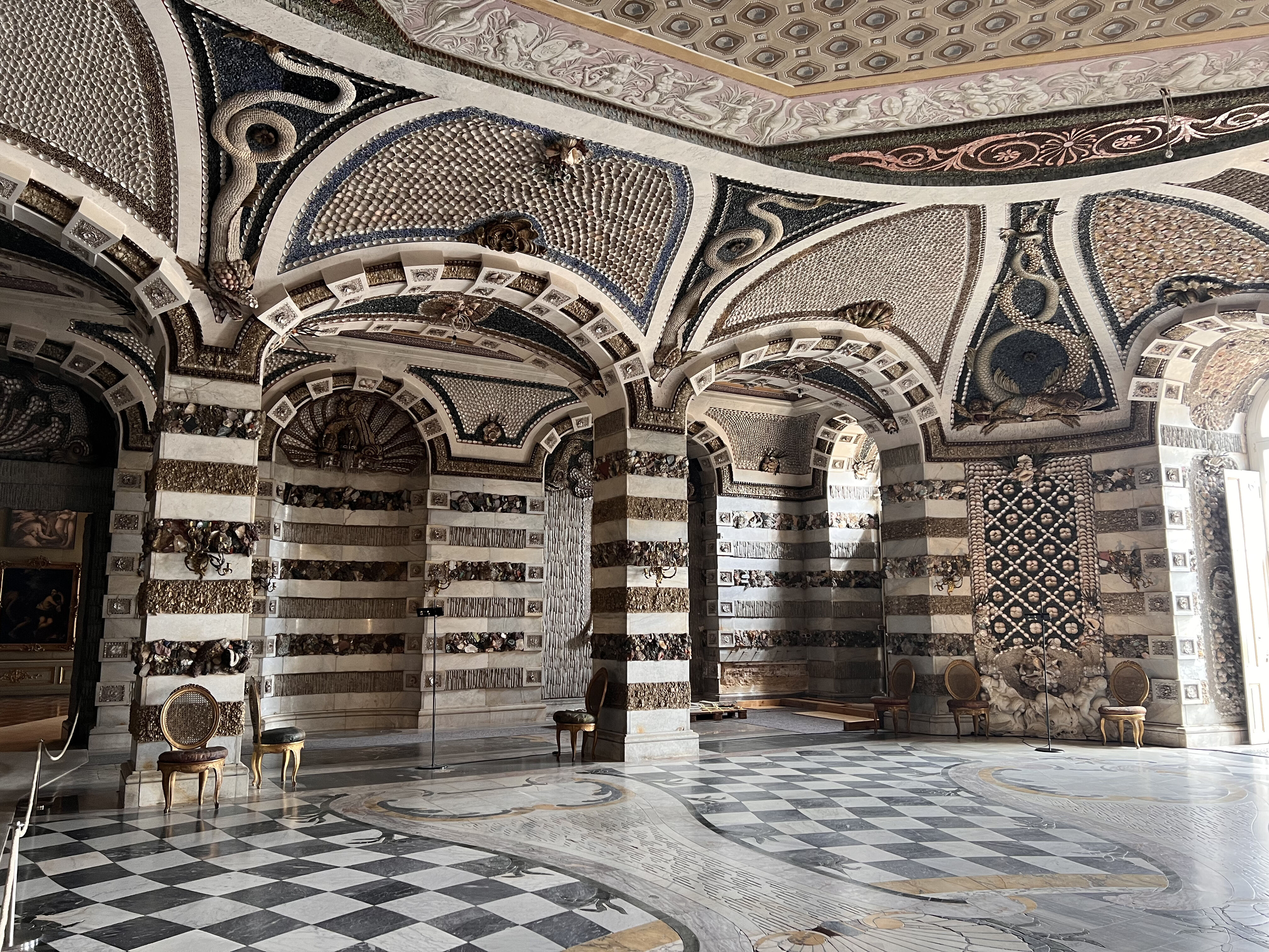 Innenaufnahme des Muschelsaals im Schloss Sanssouci mit kunstvollen Muschelverzierungen, Stuckdecken und barocken Ornamenten in hellem Gold und Weiß.