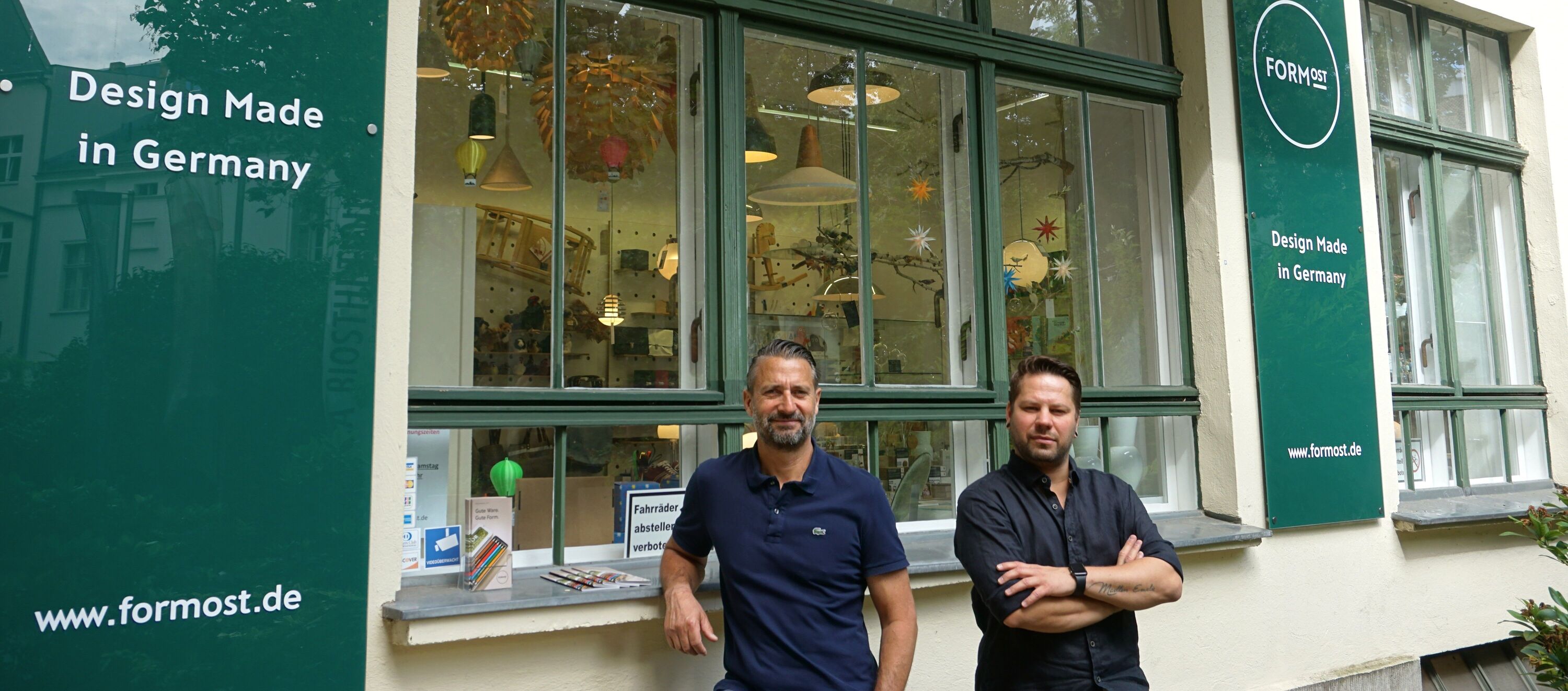 Store Manager Marcel und Geschäftsführer Christian Allihn stehen lächelnd vor der FORMOST-Ladenfassade mit grünem Logo-Schild „FORMOST - Design Made in Germany" in den Berliner Hackeschen Höfen.