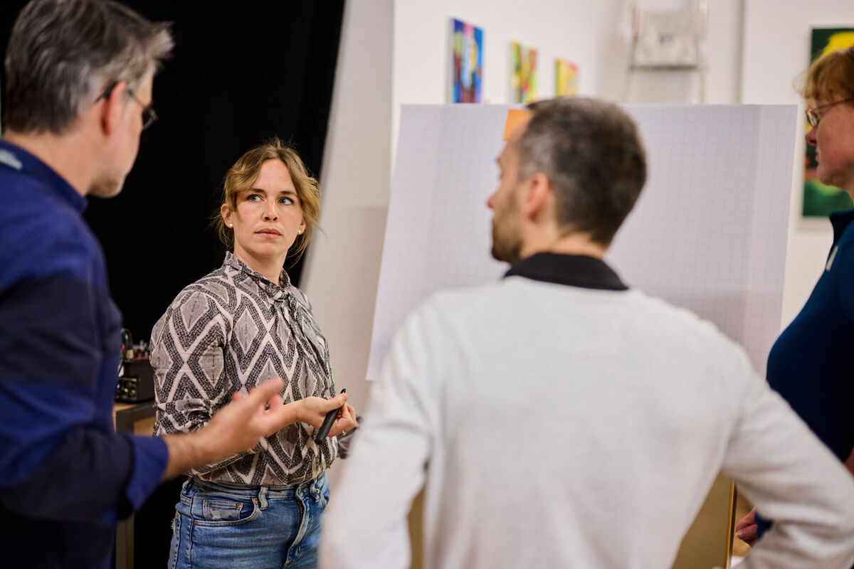 Team-Mitglieder im Strategie-Workshop zur digitalen Immobilienplattform, vor einem Flipchart mit Diagrammen und Notizen zum Leadmanagement.