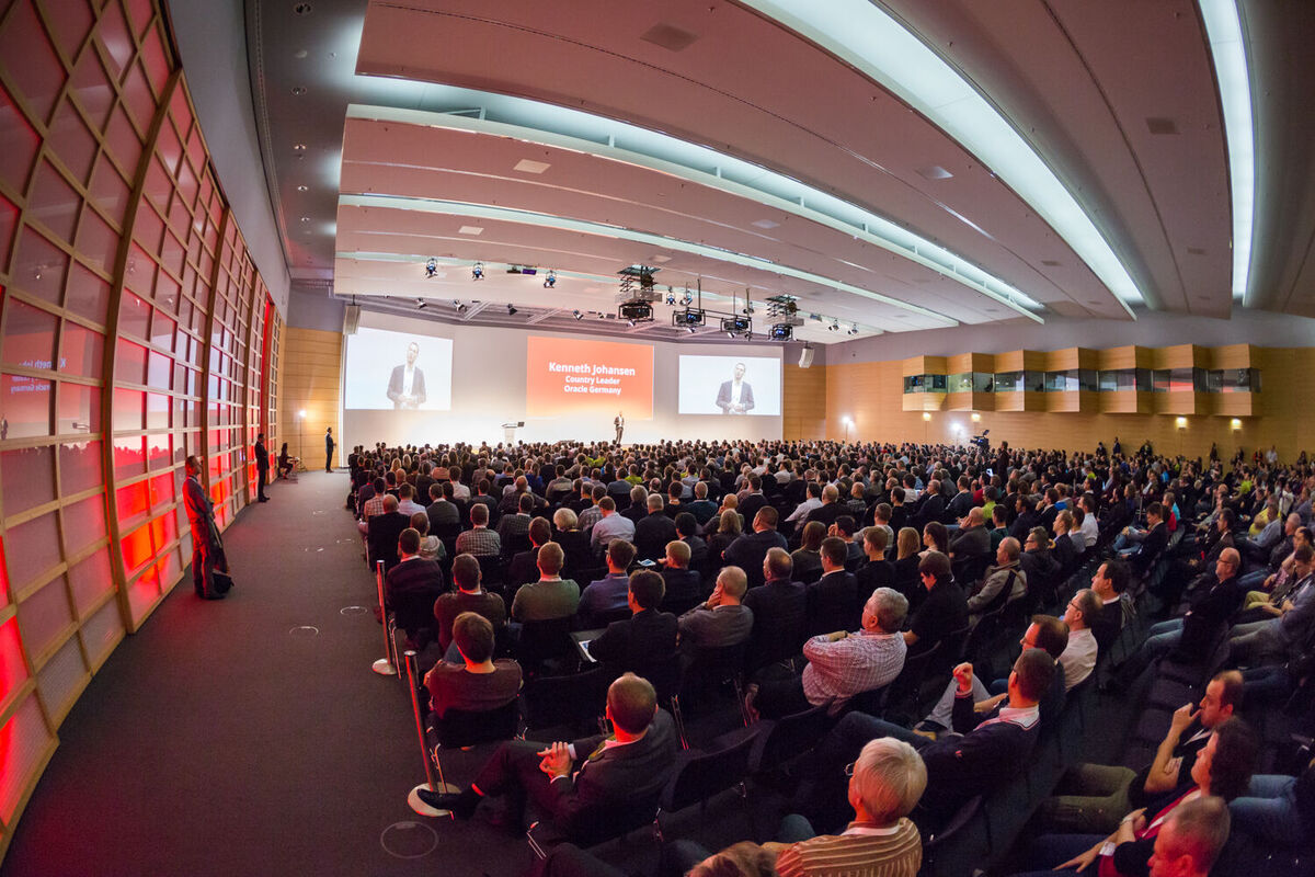 DOAG Digitale Agenda Konferenz – Orientierung für Teilnehmende Teilnehmende einer DOAG-Fachkonferenz orientieren sich im umfangreichen Veranstaltungsprogramm während eines Vortrags.