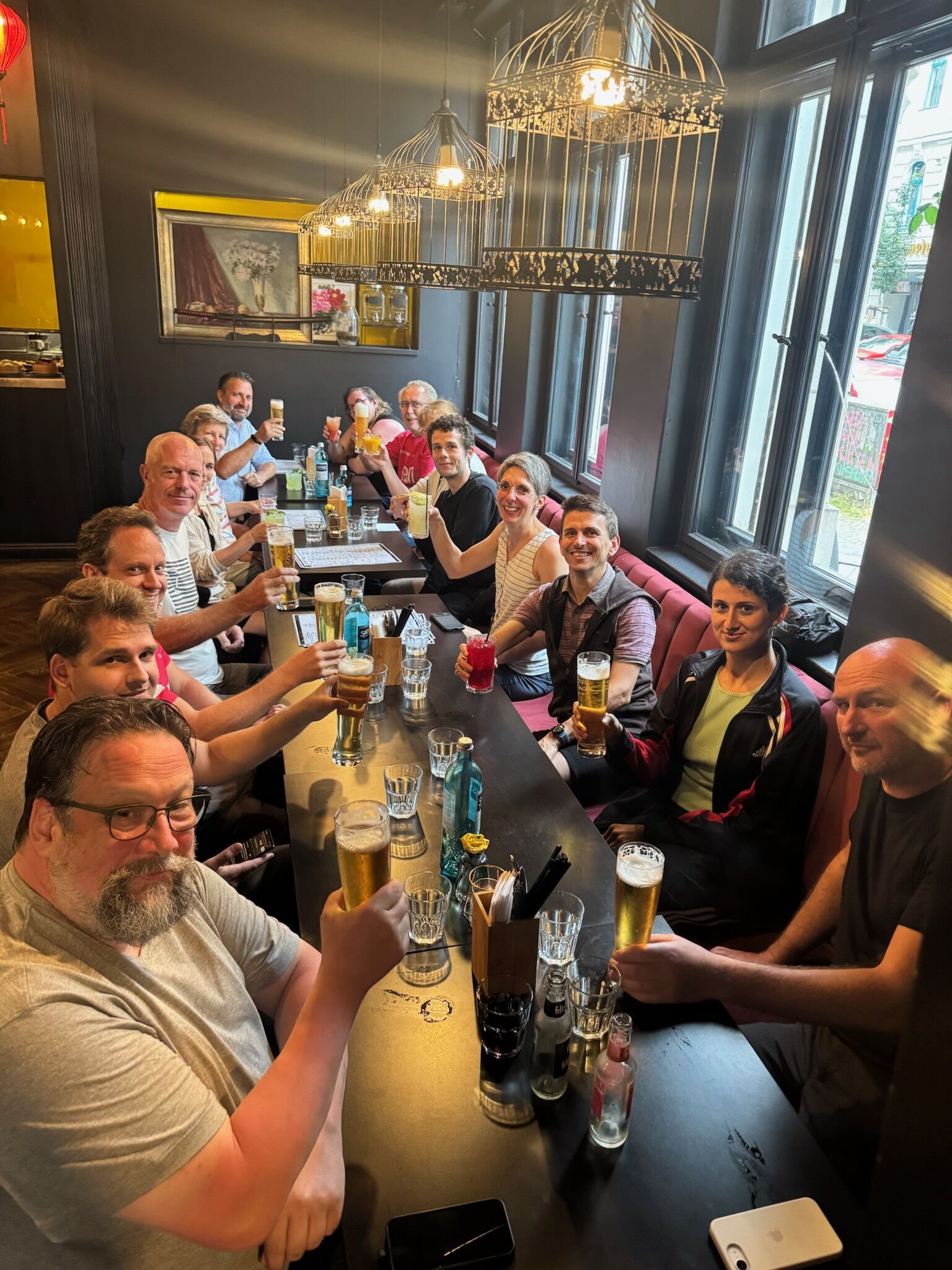 Eine Gruppe Kolleginnen und Kollegen stößt fröhlich mit Getränken an und genießt gemeinsam einen entspannten Abend im Restaurant.