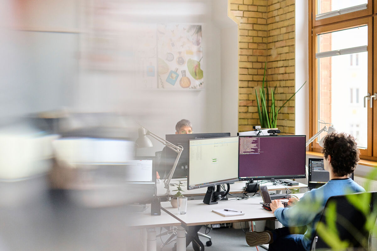 Konzentriertes Arbeiten bei escape Zwei escape-Teammitglieder konzentriert am Arbeitsplatz mit mehreren Bildschirmen