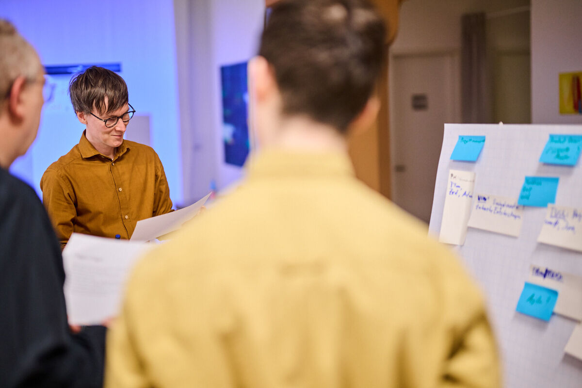 Drei Entwickler im Workshop mit Flipchart und Unterlagen planen die Entwicklung eines individuellen Kundenportals